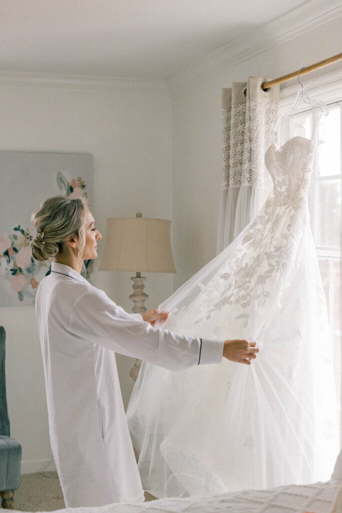 heron hill wedding | bride holding and looking at wedding dress in window