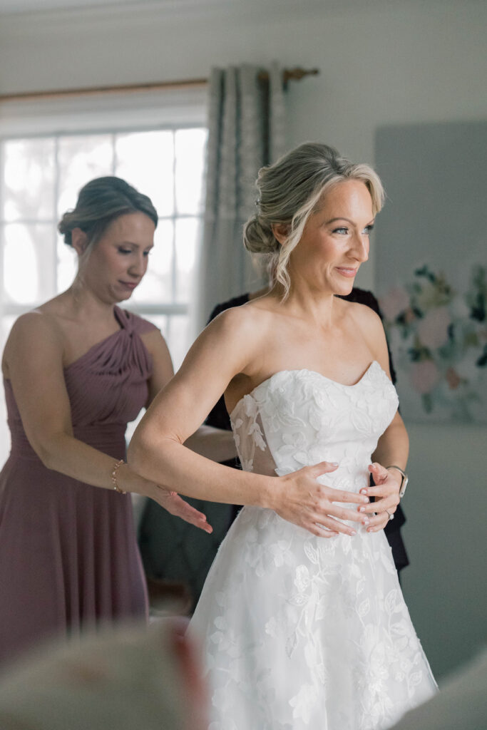 heron hill wedding | bride getting ready with mom and sister zipping her dress