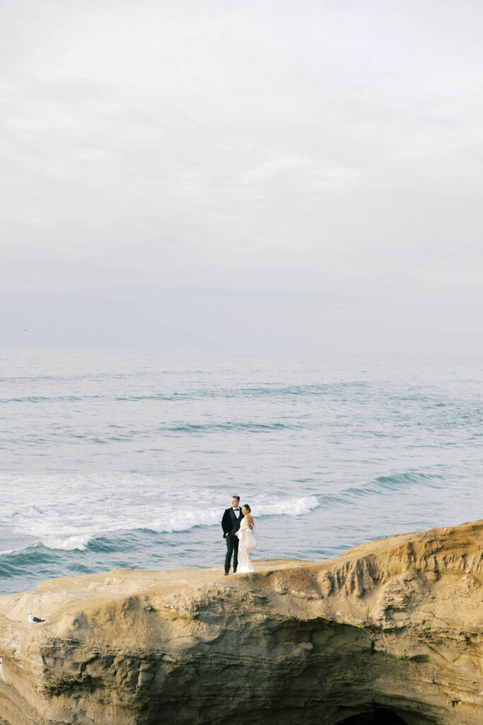 luxury wedding ideas | Couple standing together on cliff in front of pacific ocean