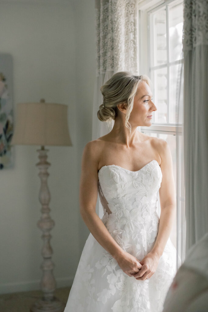 luxury wedding photographer | Bride with wedding dress on looking out the window at heron hill wedding venue