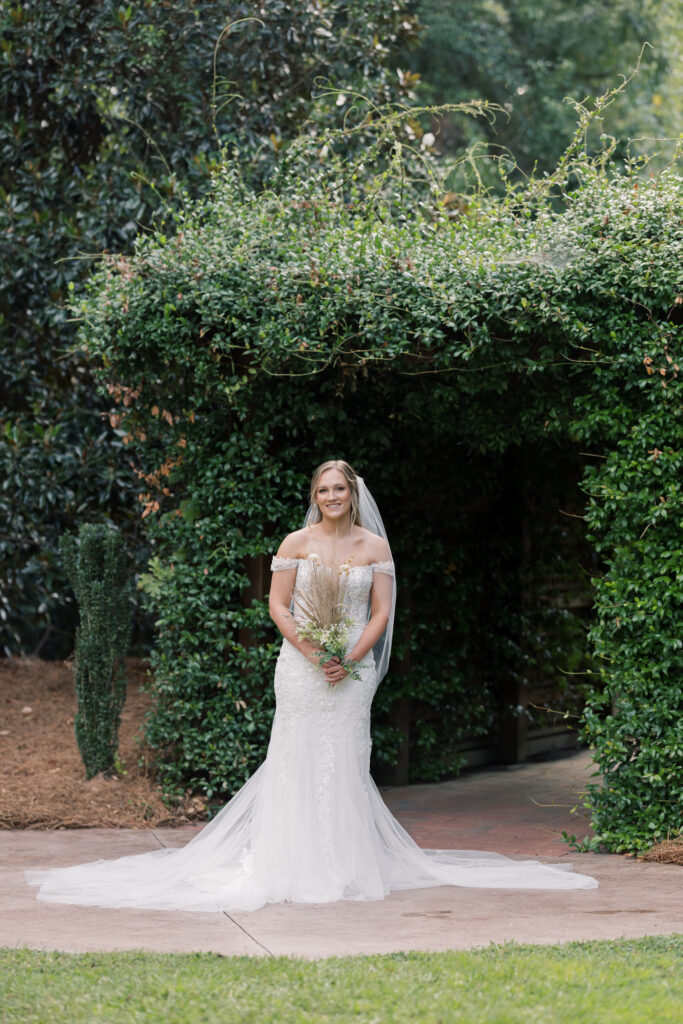 Bridal Portraits | bride standing in front of vine covered arch at southern oaks wedding venue in gilbert