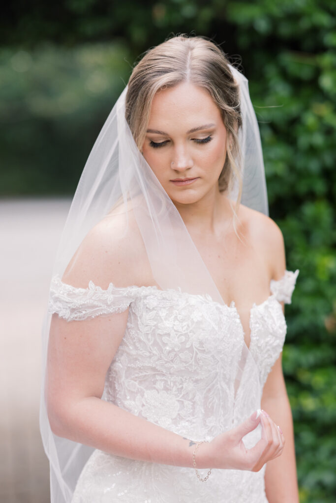 Bridal Portraits | Bride looking down holding veil at southern oaks wedding venue