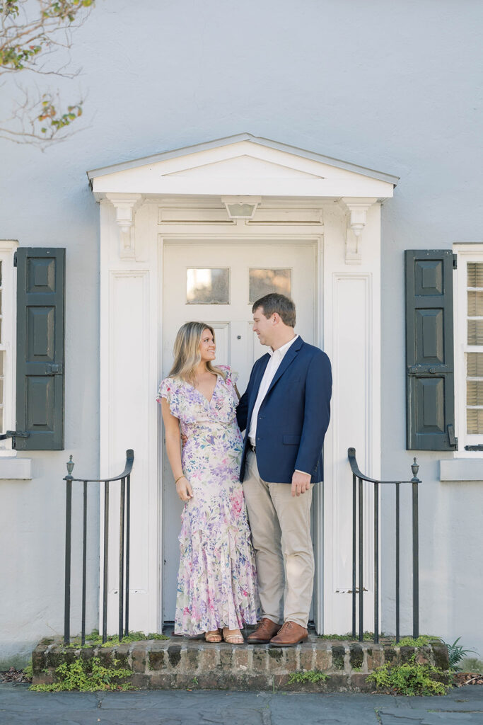 Charleston SC engagement photos | couple standing on porch of blue house