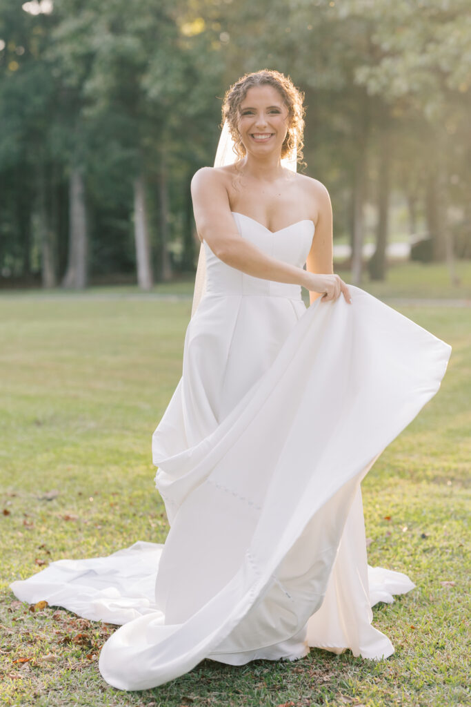  Bridal Portraits | bride holding bottom of wedding dress smiling