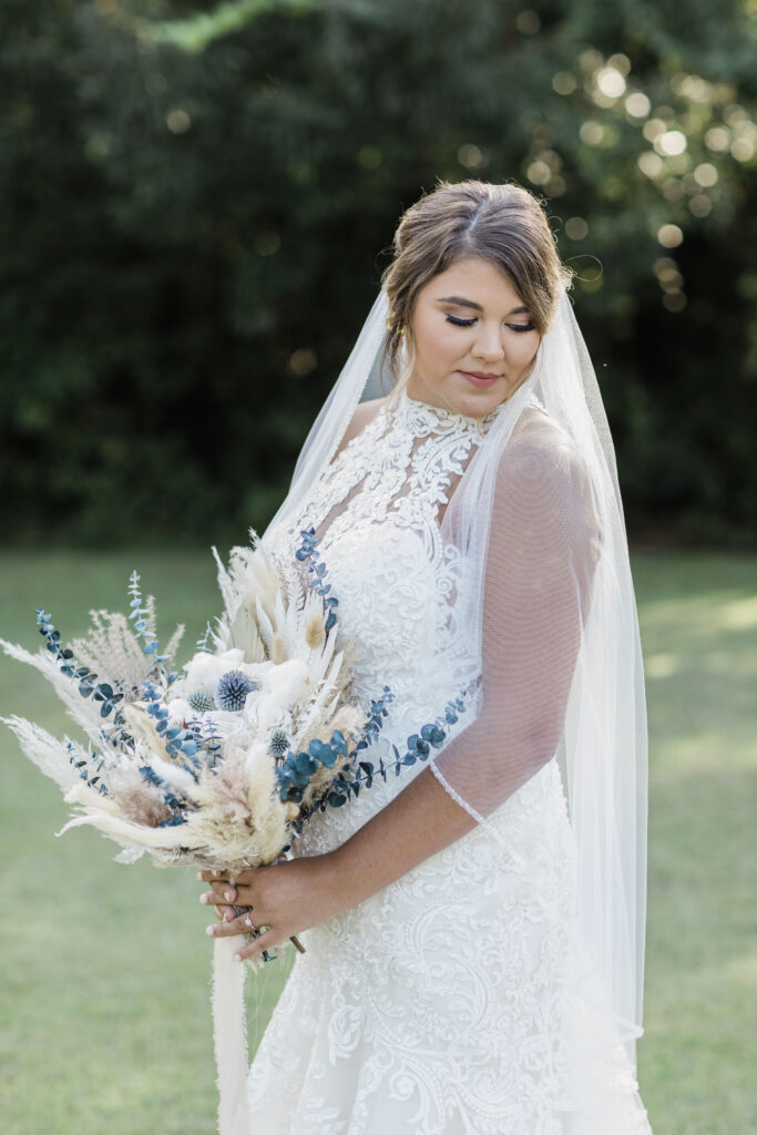 Bridal Portraits | Bride looking down and holding her bouquet. Warm summer day in Charleston, SC.