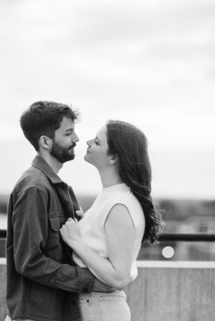 Film Photographer | 35mm film black and white image of a couple looking at each other on parking garage during engagement photos.