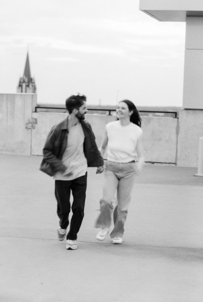 Film Photographer | black and white 35mm film image of couple running in parking garage. Engagement photo in Columbia, South Carolina.