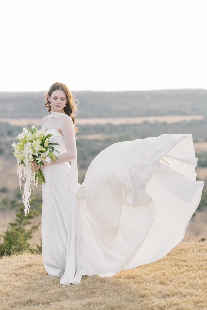 Bridal Portraits | Bride on top of bluff with wind blowing her dress. Elopement at Contigo Ranch in Fredericksburg Texas