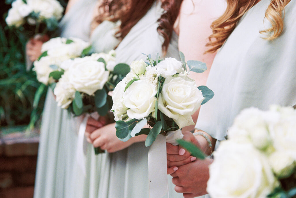 Film Photographer | Side shot of bridal party holding bouquets of white roses. 35mm color film photographed before wedding. Wedding photos at 701 Whaley in Columbia, South Carolina.