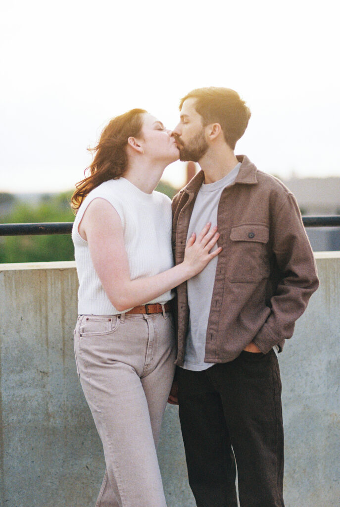 Film Photography | Beautiful couple kissing on top of rooftop in Charleston South Carolina. Photographed during engagement session. Photographed in 35mm color film.