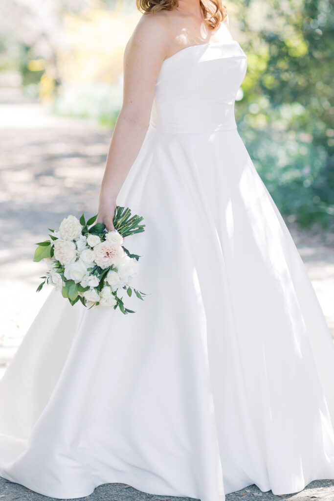 Best bridal portrait locations | Bridal portraits of bride in strapless dress in Charleston, SC. Bride is holding florals down in the shaded garden.