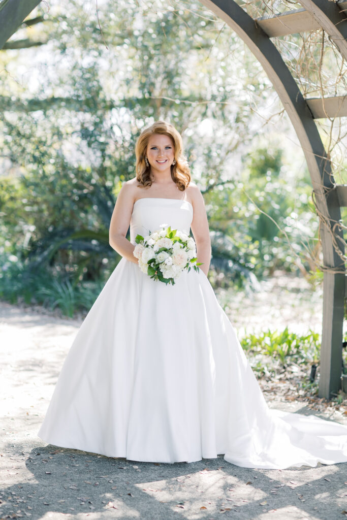 Best bridal portrait locations | Bridal portraits of bride in strapless dress in Charleston, SC. Bride is under arbor in garden.