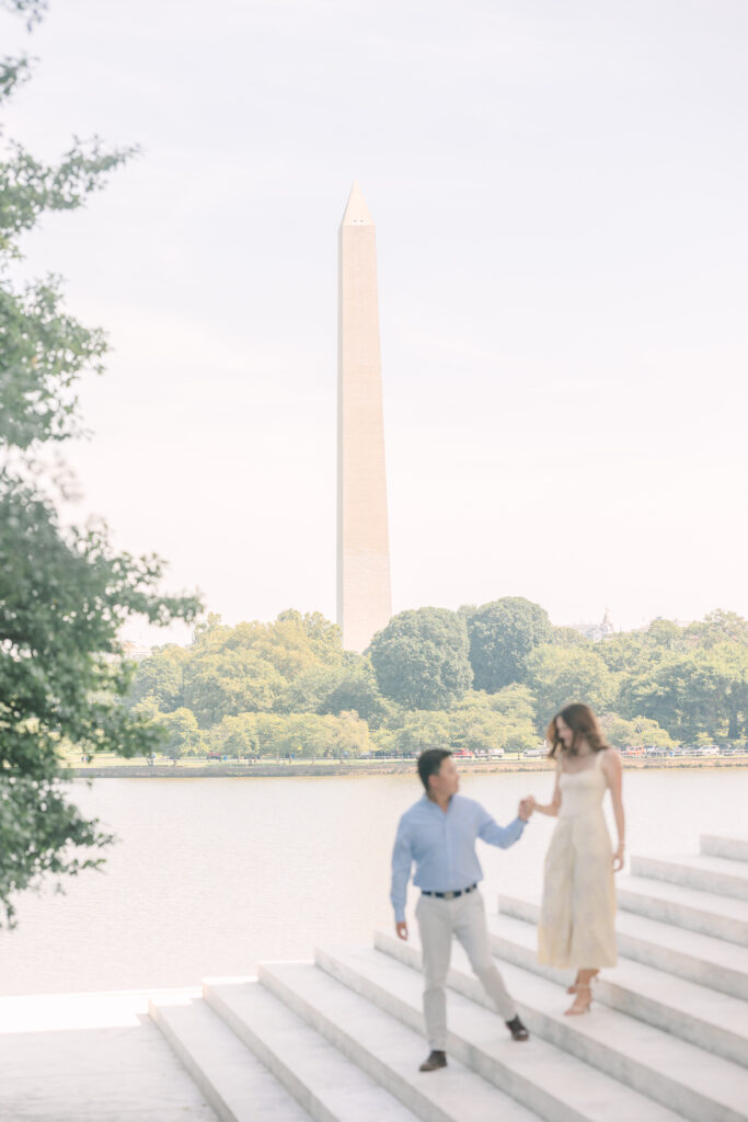DC Engagement Photographer | Engagement session in Washington, DC | couple holding hands and walking down the stairs with the Washington Monument in the background