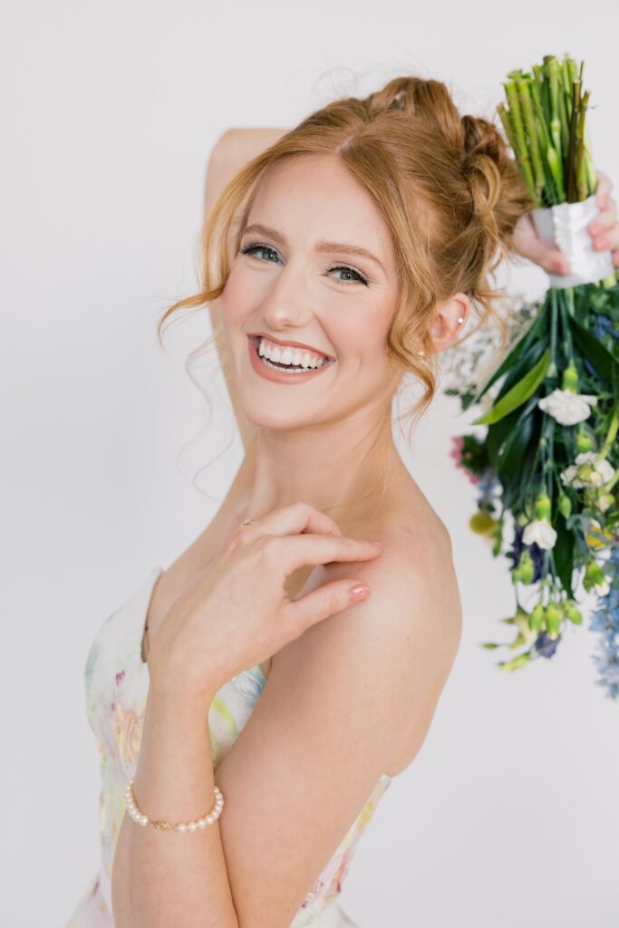 Bridal Portraits | Redhead bride smiling at the camera holding bouquet.