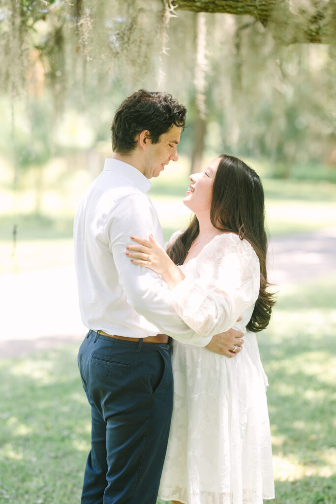 Charleston engagement photographers | Engagement session in Charleston SC | couple smiling at each other with spanish moss in background