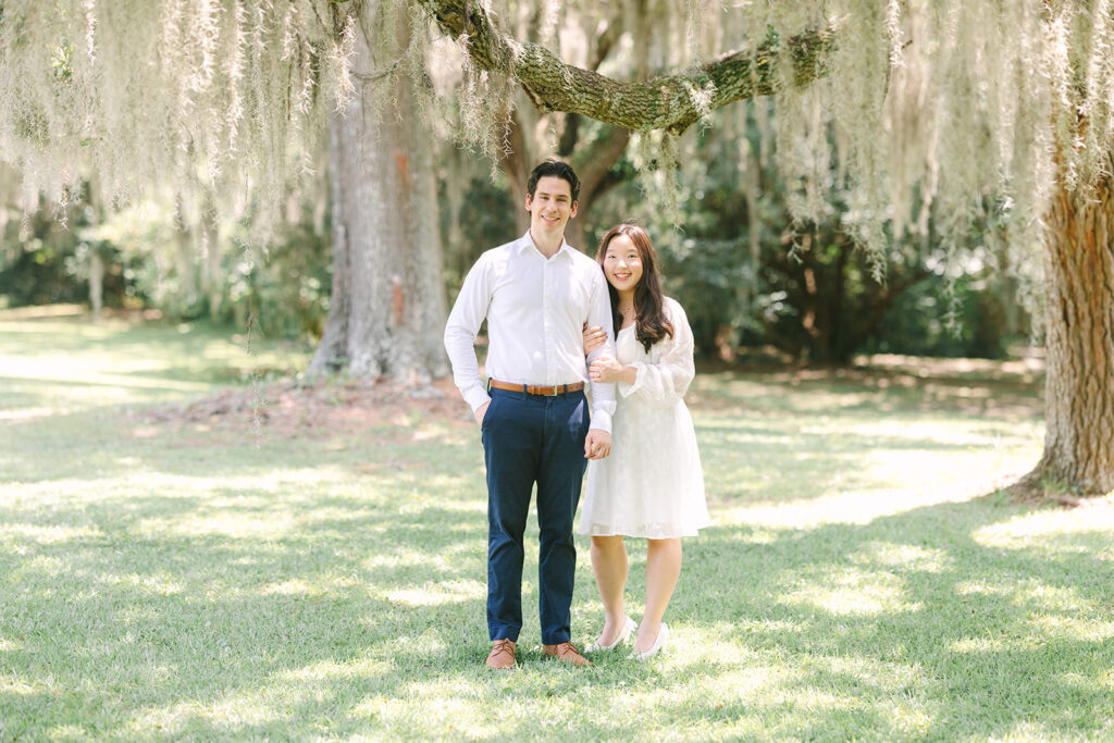 Charleston engagement photographers | Engagement session in Charleston SC | couple smiling at camera while surrounded by trees covered in spanish moss