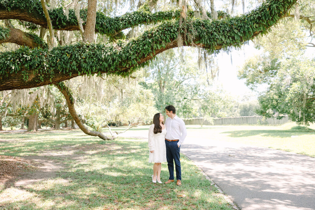Charleston engagement photographers | Engagement session in Charleston SC | couple looking at each other under large oak tree covered with vines and moss