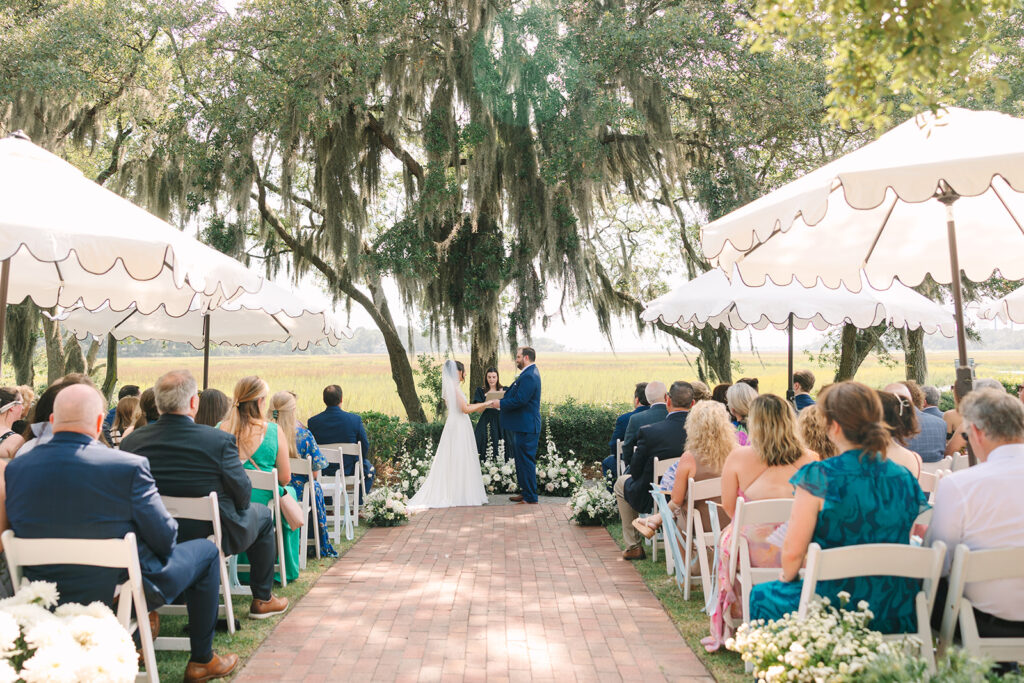 Charleston wedding Photographer | Creek at Ion Wedding | Wedding Ceremony | Bride and groom saying vows in front of guests under umbrellas
