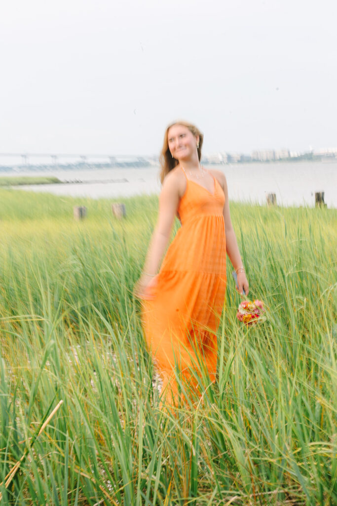 Charleston Senior Pictures | Senior Session in Charleston SC | senior in orange dress standing in the marsh looking away