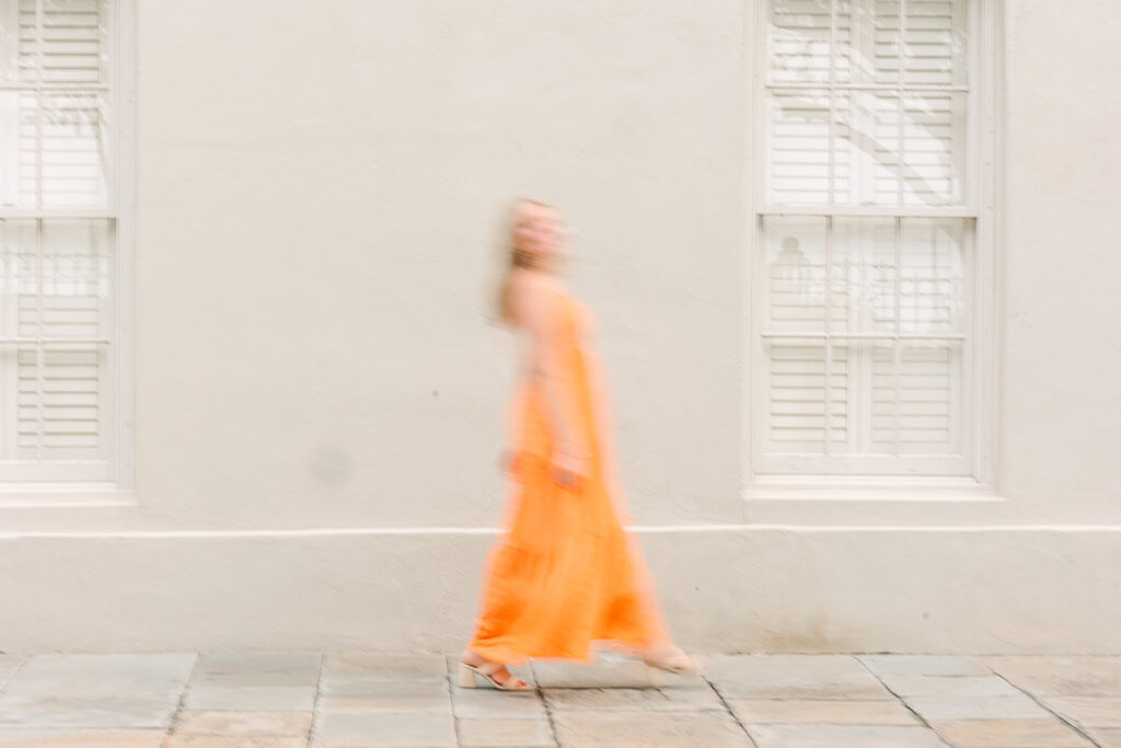 Charleston senior pictures | Senior session in Charleston SC | Blurry photo of senior in orange dress walking