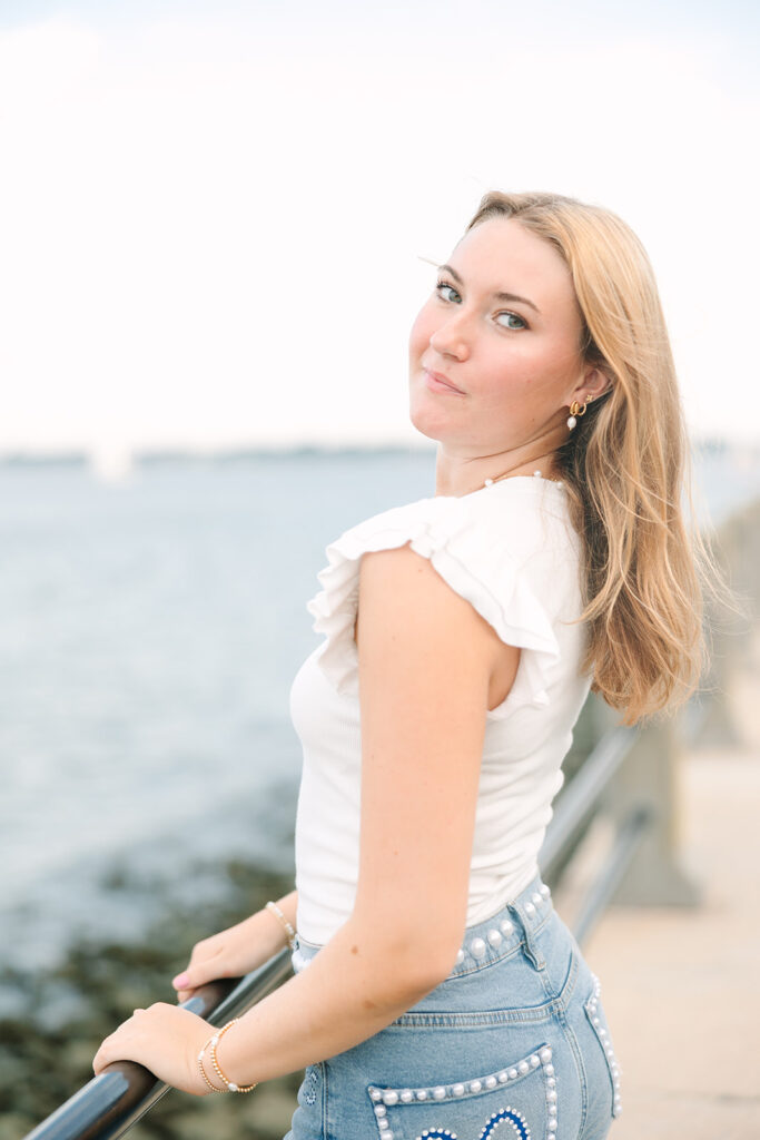Charleston Senior Pictures | Senior Session in Charleston SC | Senior looking at camera while holding on to railing at charleston harbor