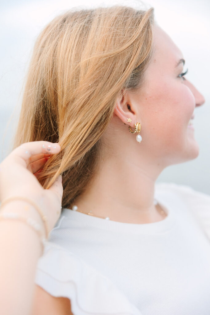 Charleston Senior Pictures | Senior Session in Charleston SC | senior holding her hair back to show her shell and pearl earrings