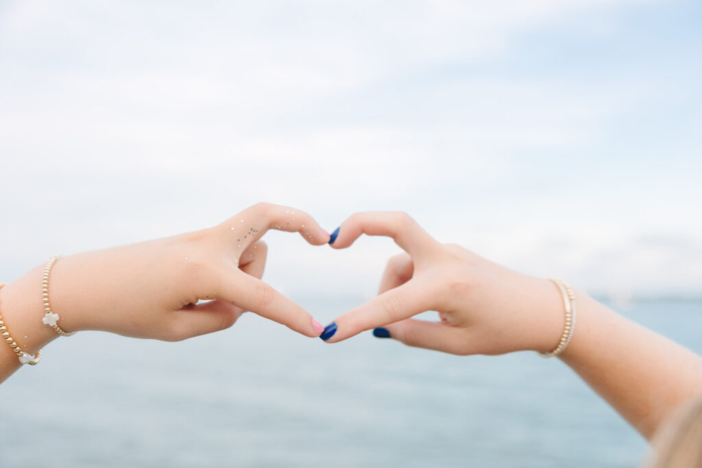 Charleston Senior Pictures | Senior Session in Charleston SC | senior making a heart out of fingers in front of the charleston harbor