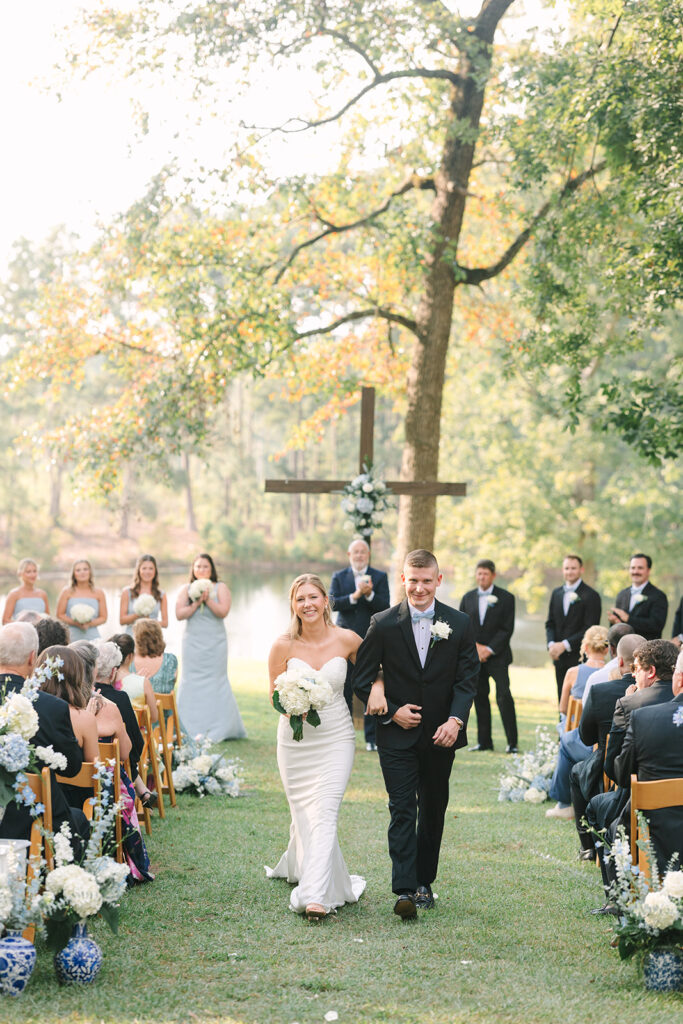 The bride and groom walk down the aisle after their ceremony as guests look on, capturing a joyful and unscripted moment typical of experienced Columbia SC wedding photographers.