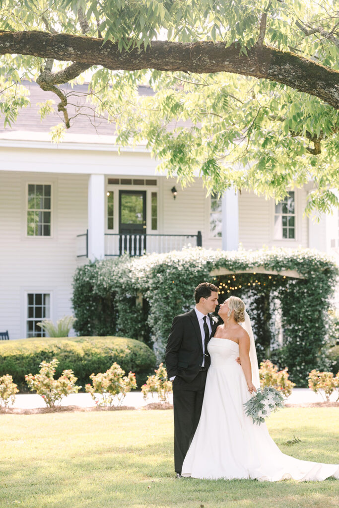 Wedding Photographers in Columbia SC | Stee Garman Photography Fine-art Wedding Photographer | Bride and groom embrace under a large tree in front of a white house with lush greenery