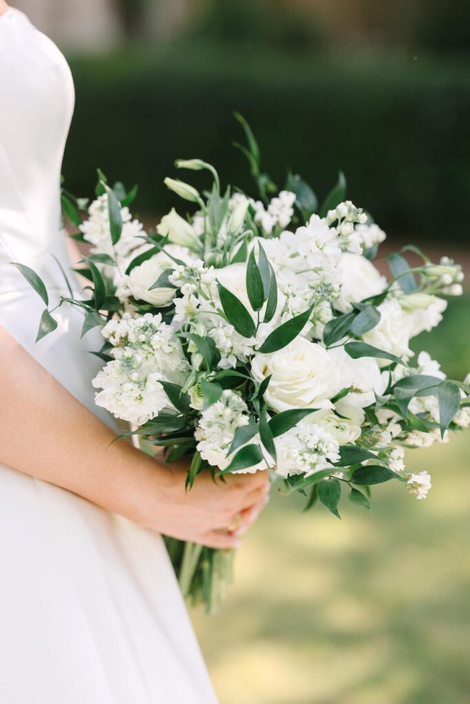Bridal Portraits Photographer Columbia SC | Stee Garman Photography Fine-art Wedding Photographer | Bride holding elegant bouquet of white roses and greenery against a blurred nature background, evoking a sense of beauty and celebration.