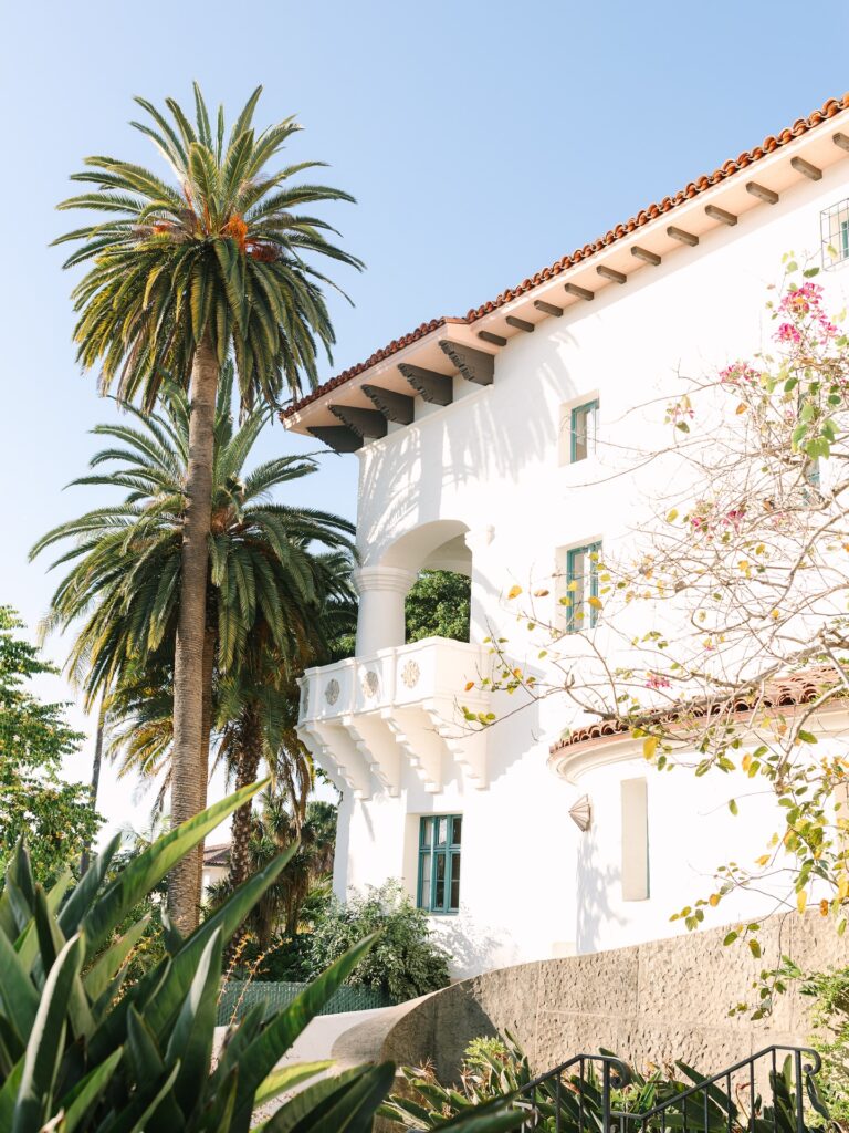 A white stucco building with palm trees and architectural detailing offers a bright and airy setting, representing unique destination-style wedding venues near Columbia SC.