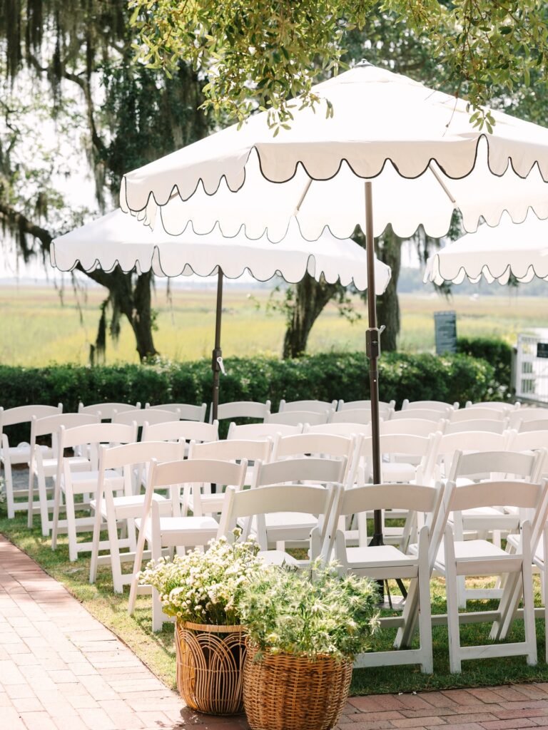 Rows of white chairs sit beneath shaded umbrellas along a brick aisle, creating a polished ceremony layout often seen at garden wedding venues in Columbia SC.