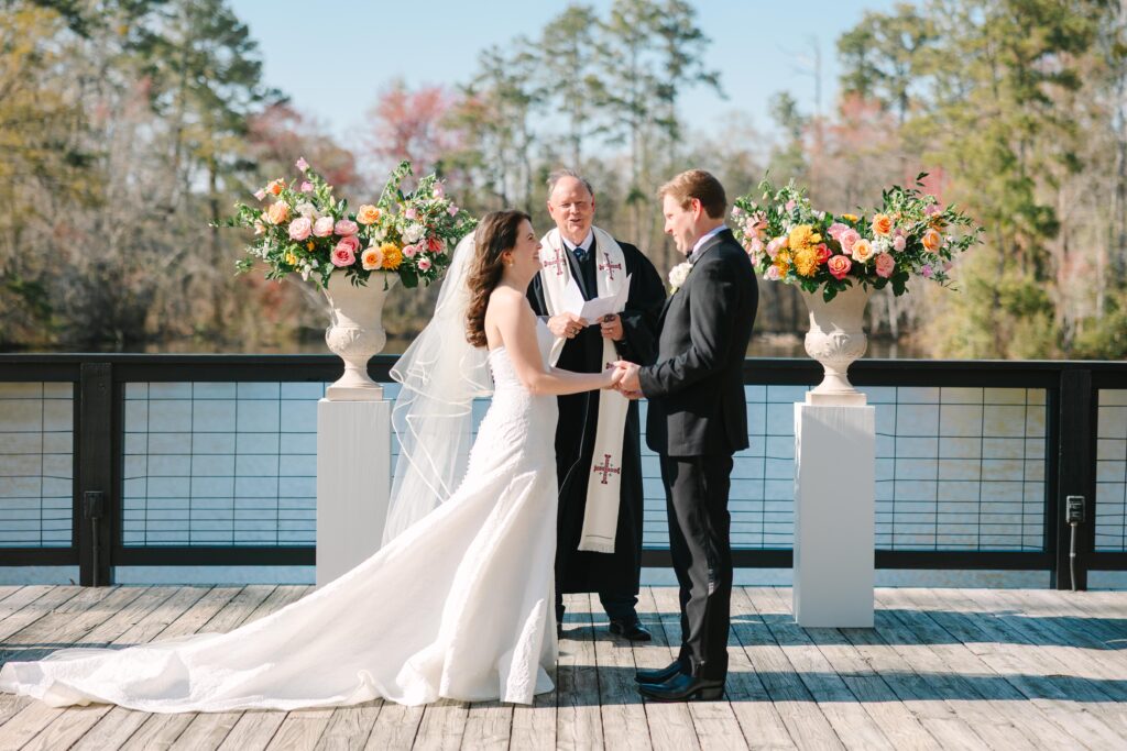 Photography Columbia SC | Stee Garman Photography Fine-art Wedding Photographer | A couple stands holding hands during an outdoor wedding ceremony by a lake. 