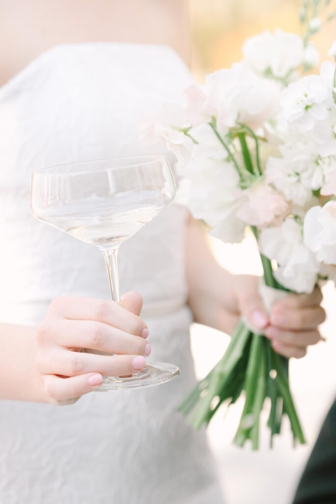 Columbia SC Wedding Photographers | Stee Garman Photography Fine-art Wedding Photographer | A bride in a strapless white dress holds a champagne glass and a bouquet of white and soft pink flowers.