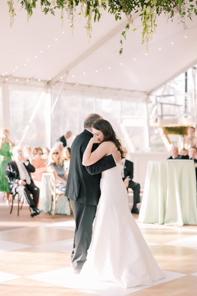 A bride shares a slow dance with an older man under a softly lit reception tent, capturing an emotional moment often preserved by experienced Columbia SC photographers.