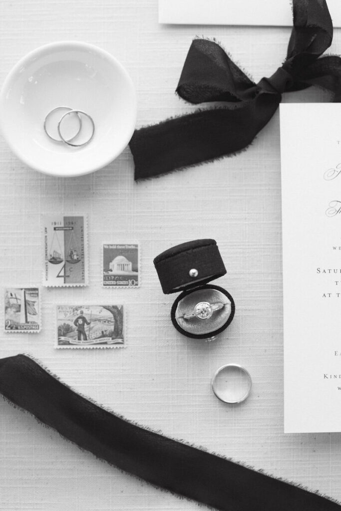 Flat lay of wedding rings, invitation pieces, ribbon, and heirloom details arranged in a refined monochrome composition for Wavering Place Plantation wedding photography.