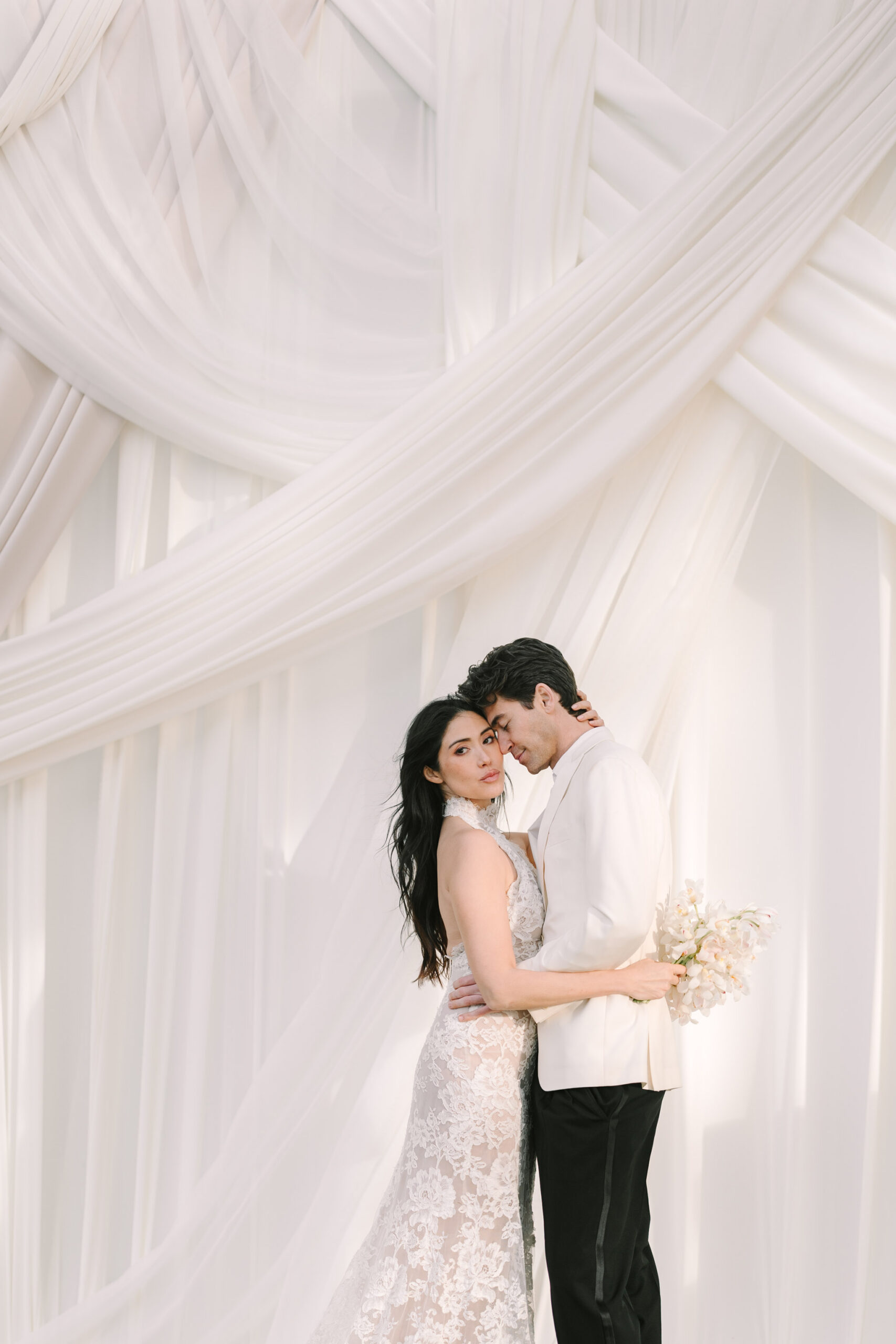 Bride and groom standing beneath soft white drapery during a romantic portrait at Lowndes Grove, a historic Charleston waterfront wedding venue photographed by Charleston wedding photographer Stee Garman Photography.