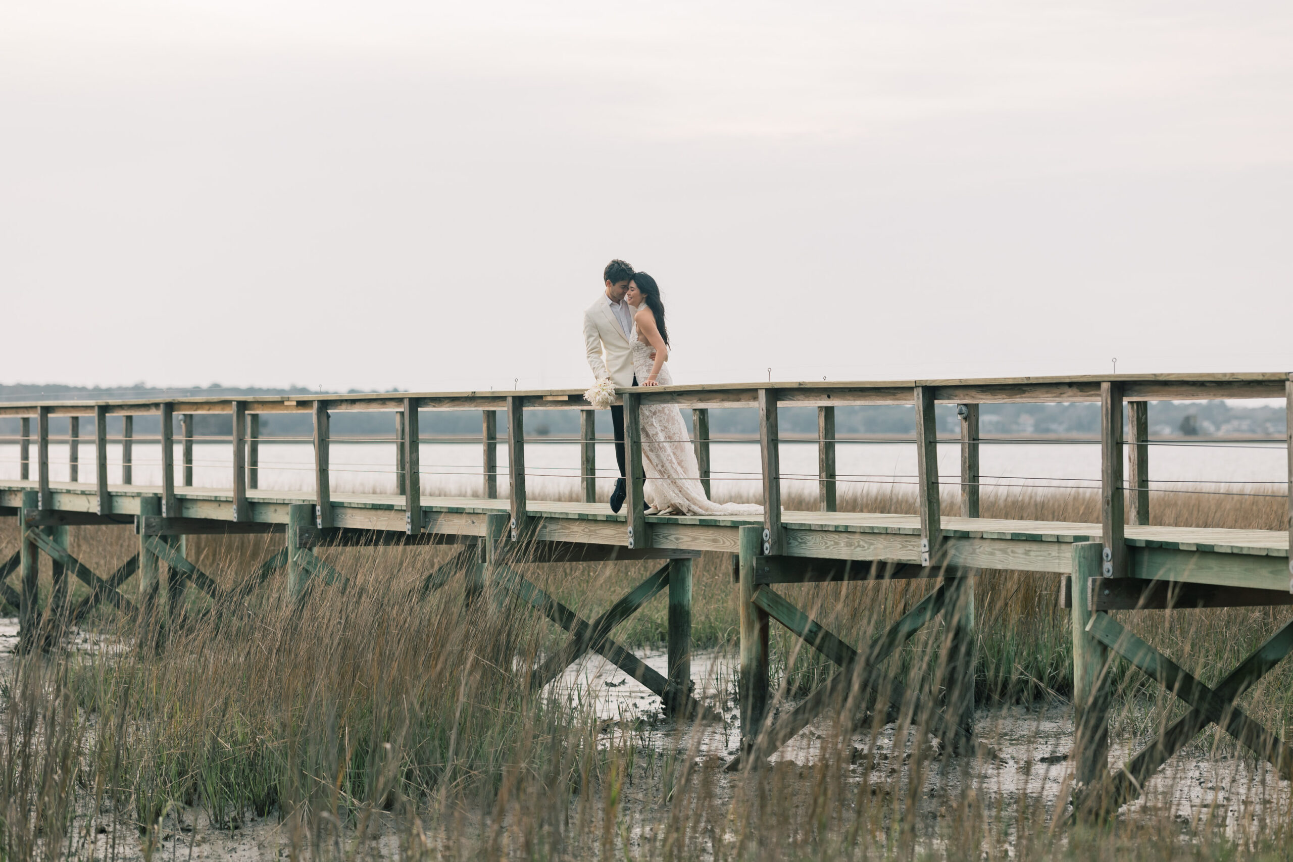Bride standing on the waterfront dock at Lowndes Grove overlooking the Charleston harbor during a Charleston wedding photography session by Stee Garman Photography.