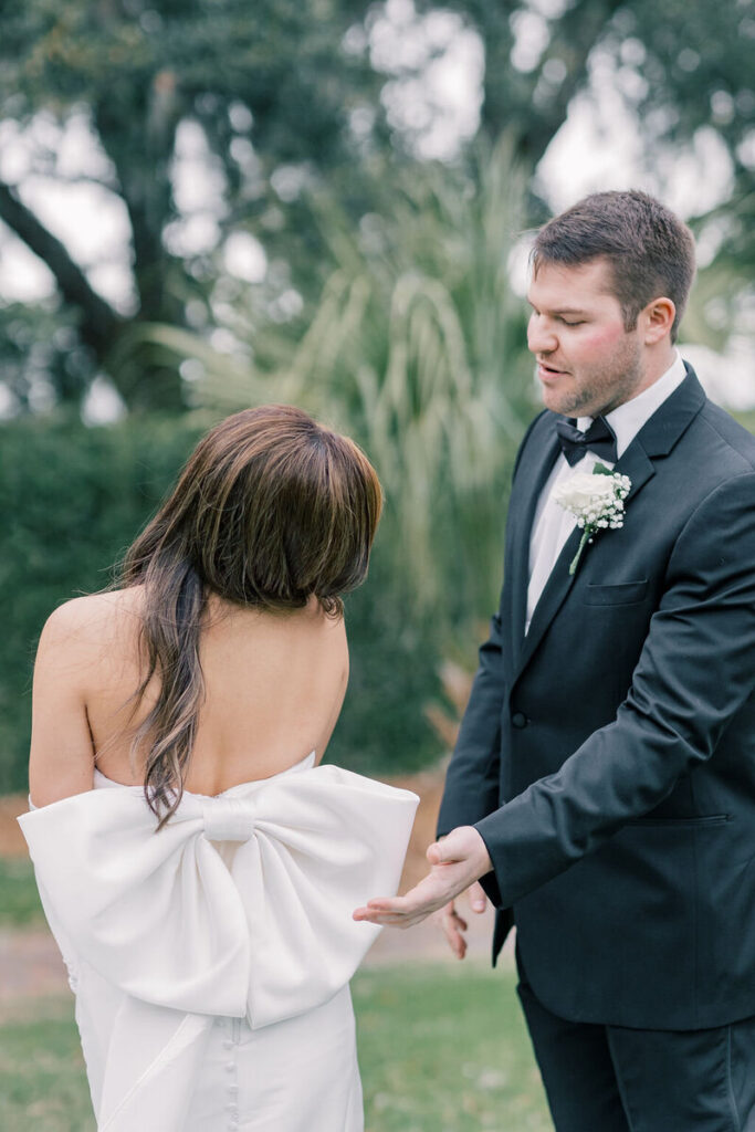 A groom reaches for the bride’s hand as they stand outdoors, creating a candid interaction that reflects the authentic style of Columbia SC photographers.