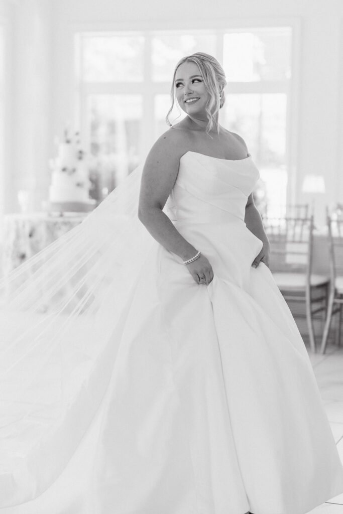 Bride standing in soft window light as her full gown and veil fall around her in an elegant bridal portrait, a romantic start to a Grand Holland Estate wedding in Greenville SC.