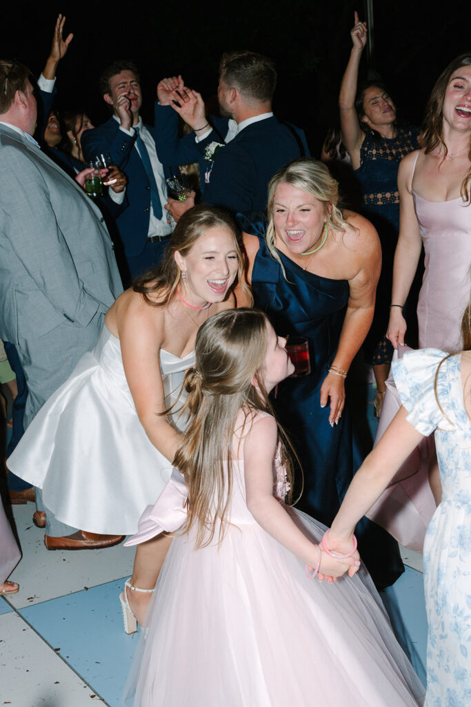 The bride crouches to dance with young flower girls while guests celebrate around them, ending the night with warmth and movement at this Botanical Gardens Clemson SC wedding.