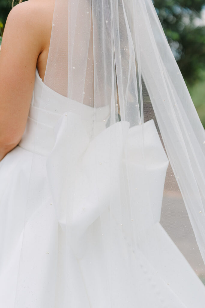 Close-up of a bride’s flowing veil and structured white wedding gown, highlighting the delicate details captured through fine-art wedding photography in Charleston.