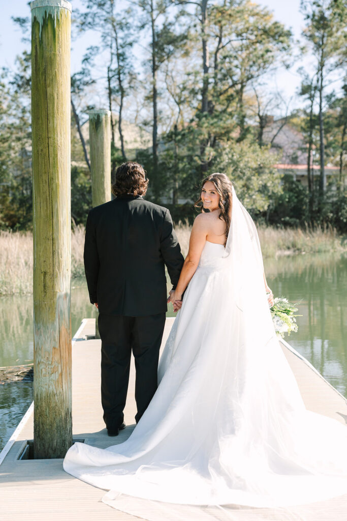 The couple walks hand in hand along a dock overlooking the water, creating a quiet just-married portrait with a Columbia SC wedding photographer.
