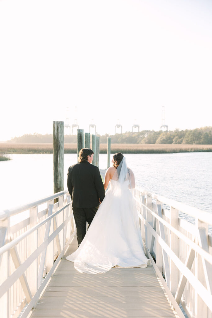 Bride and groom walk away together at the end of the dock in soft golden light, closing the day with a timeless image from Columbia SC photographers.