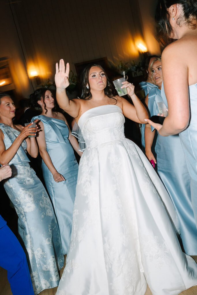 Bride dances with friends during a lively evening reception, blending movement and emotion in a candid Charleston wedding photographer style.