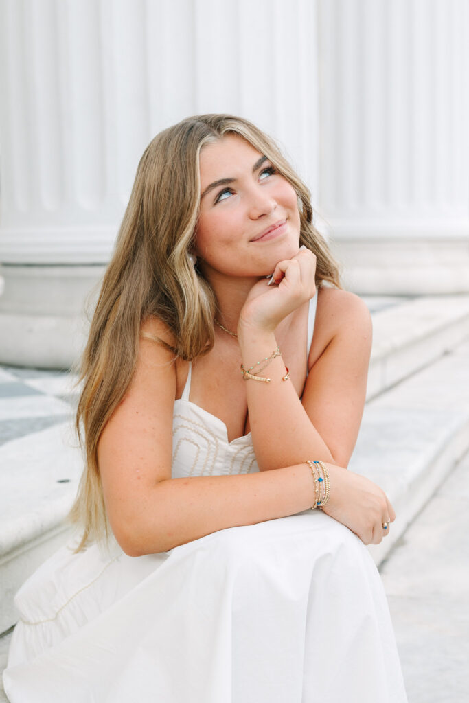 Senior sitting at columns and steps in downtown charleston at hiberian hall. Iconic checkered flooring. Photographed by Stee Garman Photography.