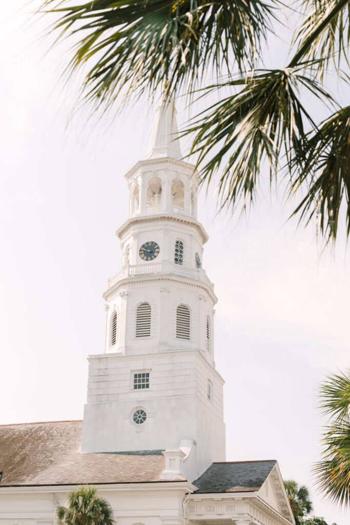 White church steeple framed by palm fronds against a bright sky, reflecting the historic character found near many Charleston wedding venues.