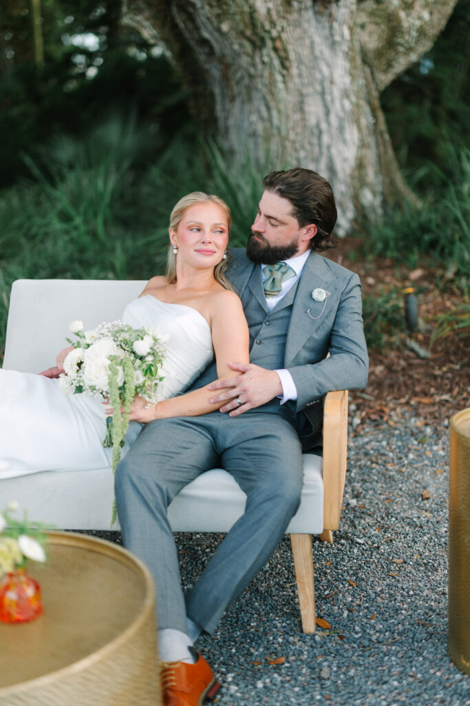 Bride and groom seated together beneath a mature oak tree at The Island House on Johns Island SC