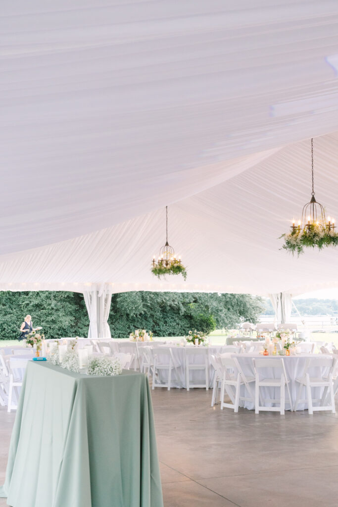 White-draped wedding reception tent with hanging florals and sage green accents at The Island House