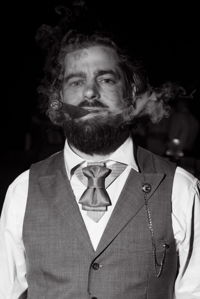 Black-and-white portrait of Taylor in his wedding vest with cigar smoke surrounding his face